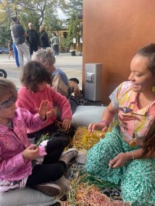 Becky Chatfield in a weaving workshop with children sitting on a mat